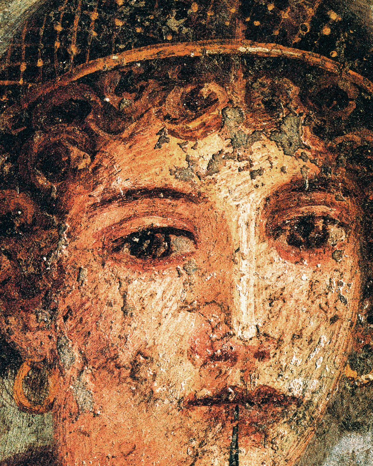 Primissimo piano degli occhi, dei riccioli e della reticella dorata di Saffo sull'intonaco screpolato
