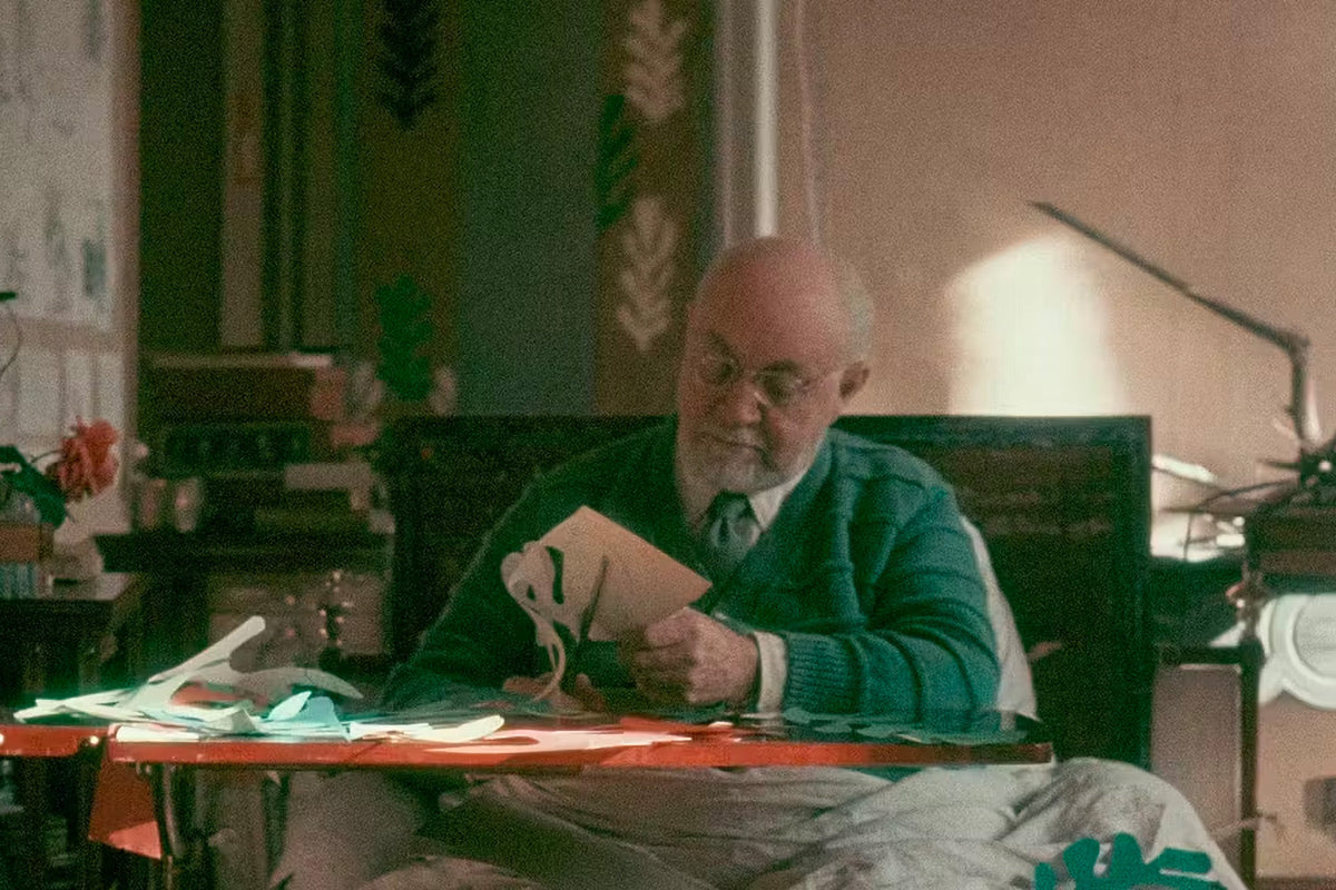 Henri Matisse negli ultimi anni di vita, al tavolo mentre ritaglia forme da fogli di carta dipinta