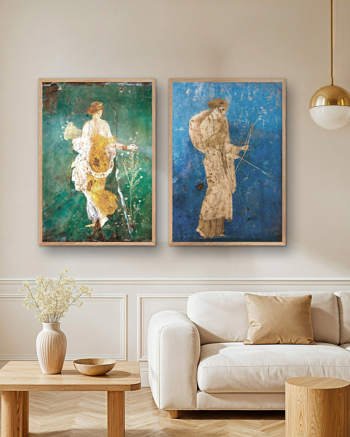 Set da 2 poster di affreschi romani, Flora e Artemide, con cornici in legno naturale sopra un divano in soggiorno